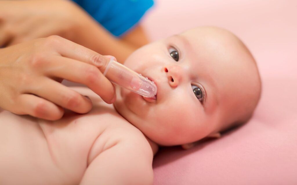 Infant Getting Gums Cleaned By Parent